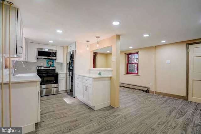 kitchen with tasteful backsplash, a baseboard radiator, light wood-style flooring, appliances with stainless steel finishes, and a sink