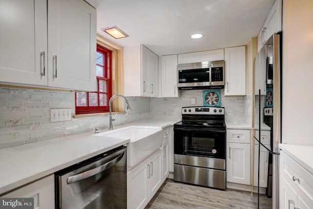 kitchen with stainless steel appliances, a sink, light countertops, and white cabinets