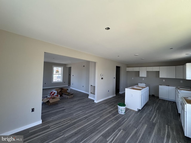 kitchen featuring dark wood-style floors, open floor plan, white cabinets, and baseboards