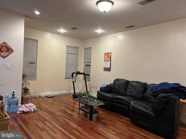 living room featuring wood finished floors, visible vents, and baseboards