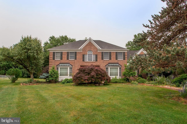 colonial-style house featuring a front lawn and brick siding