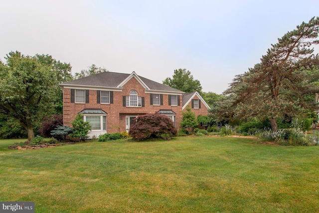 colonial home featuring a front yard and brick siding