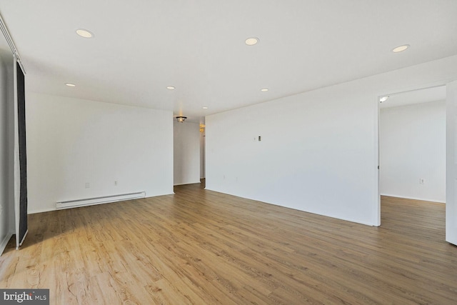 empty room featuring recessed lighting, wood finished floors, and a baseboard radiator