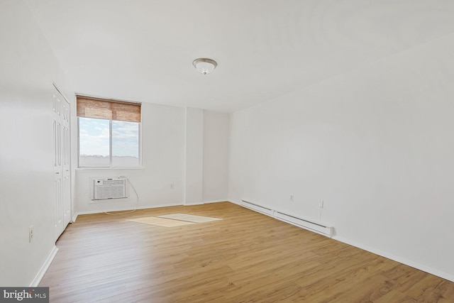 spare room with light wood-style floors, baseboards, baseboard heating, and a wall unit AC