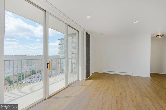 empty room featuring a baseboard heating unit, recessed lighting, and wood finished floors