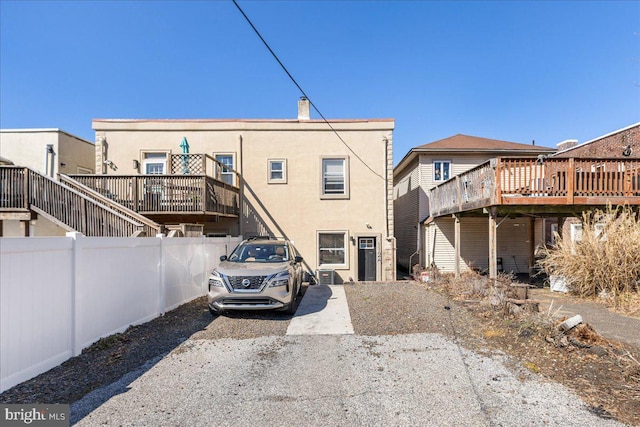 rear view of house featuring fence and stucco siding