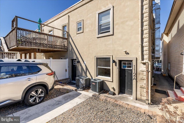 rear view of house featuring central air condition unit and stucco siding