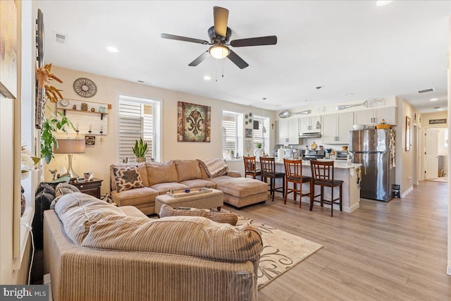 living area with ceiling fan, light wood-type flooring, visible vents, and recessed lighting