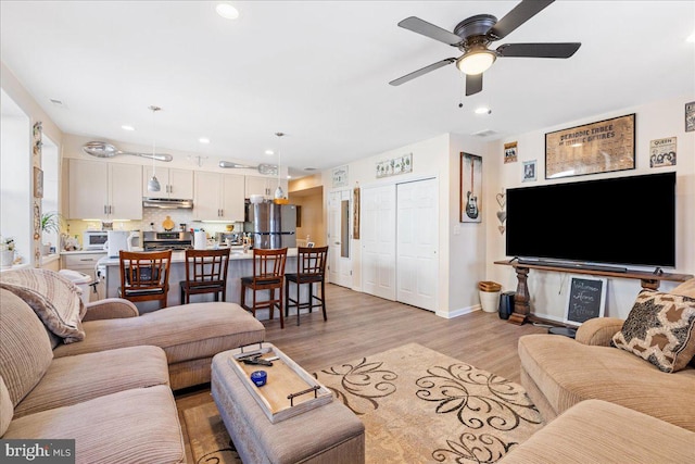 living area featuring light wood-type flooring, ceiling fan, baseboards, and recessed lighting