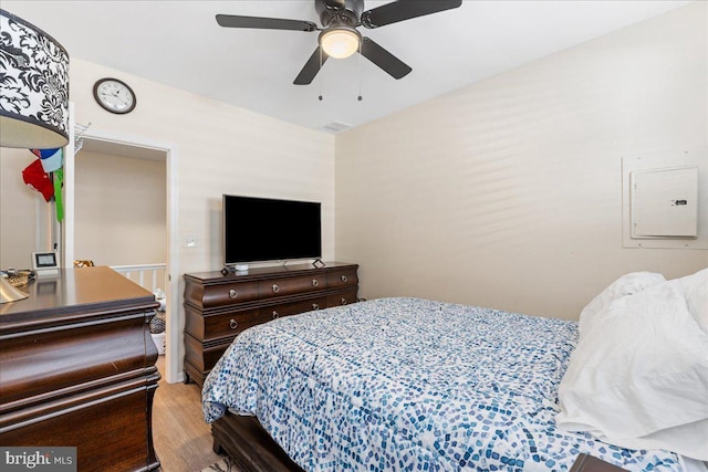 bedroom featuring electric panel, a ceiling fan, and wood finished floors