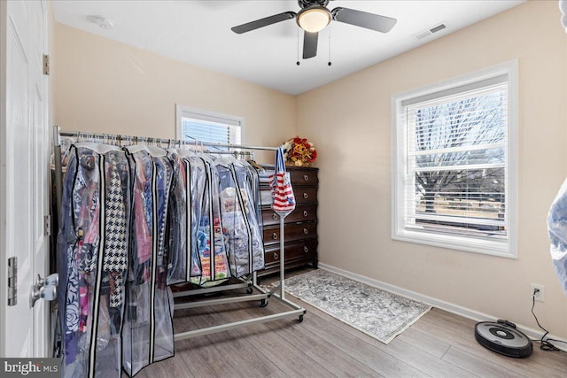 workout room with baseboards, visible vents, ceiling fan, and wood finished floors