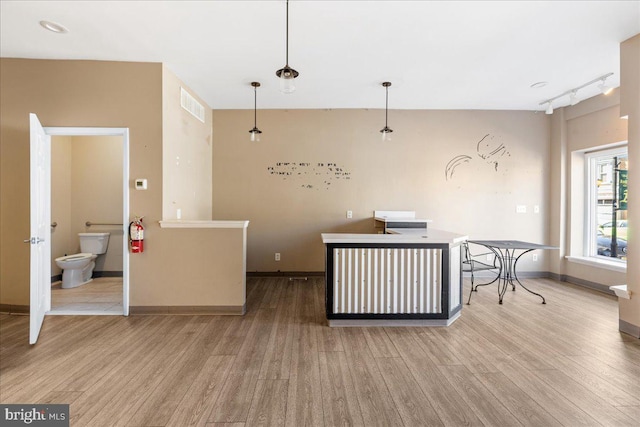 kitchen with baseboards, track lighting, visible vents, and wood finished floors