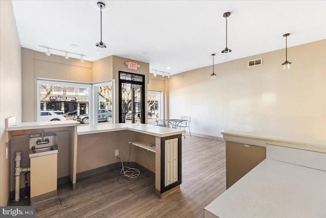 kitchen featuring track lighting, wood finished floors, visible vents, and decorative light fixtures