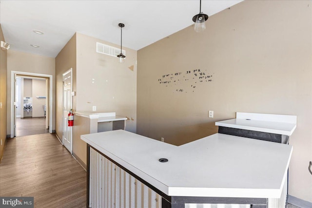 interior space featuring pendant lighting, light countertops, visible vents, wood finished floors, and baseboards