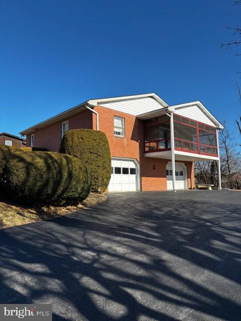 view of front of property featuring an attached garage, aphalt driveway, and brick siding