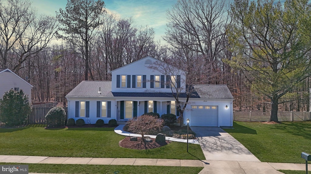 view of front of property featuring a front yard, concrete driveway, fence, and a garage