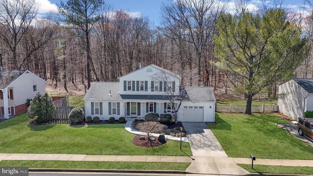 view of front of home with an attached garage, concrete driveway, a front yard, and fence