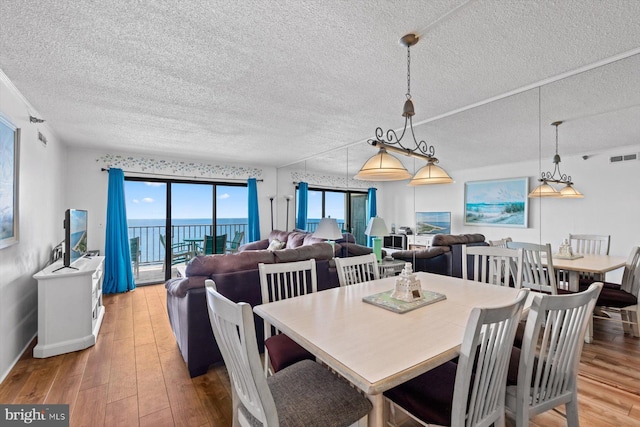 dining area featuring visible vents, a textured ceiling, baseboards, and hardwood / wood-style flooring