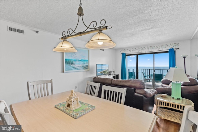 dining space featuring visible vents, a textured ceiling, and wood finished floors