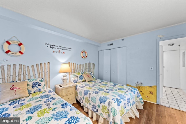 bedroom with a closet, wood finished floors, and visible vents