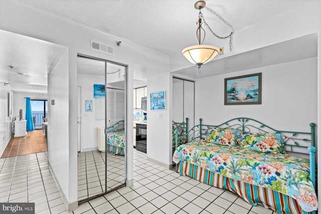 tiled bedroom featuring multiple closets, visible vents, and a textured ceiling