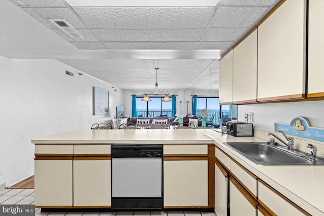 kitchen featuring visible vents, light countertops, open floor plan, a sink, and a peninsula