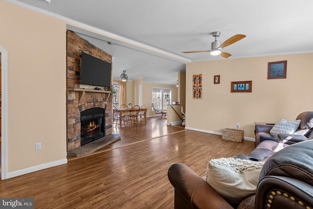 living area with a fireplace, ceiling fan, vaulted ceiling, wood finished floors, and baseboards