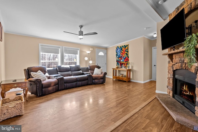 living room featuring baseboards, a fireplace, wood finished floors, and crown molding