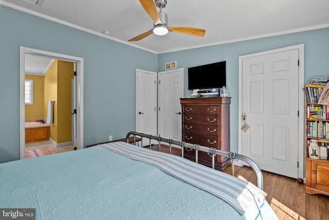 bedroom featuring ceiling fan, wood finished floors, visible vents, ornamental molding, and ensuite bath