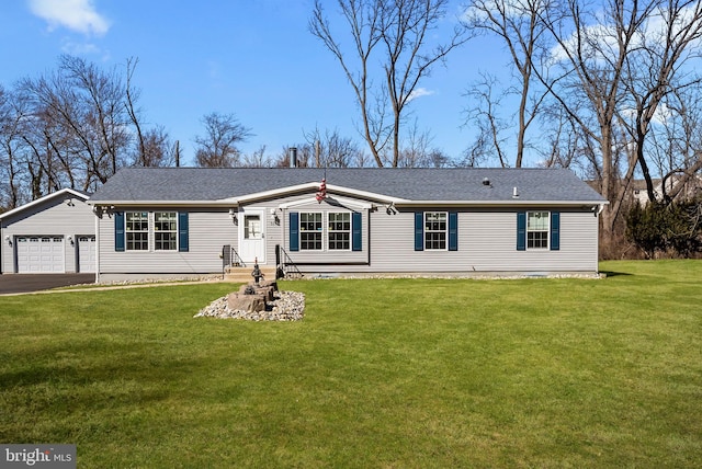 view of front facade featuring a shingled roof, an attached garage, driveway, and a front lawn