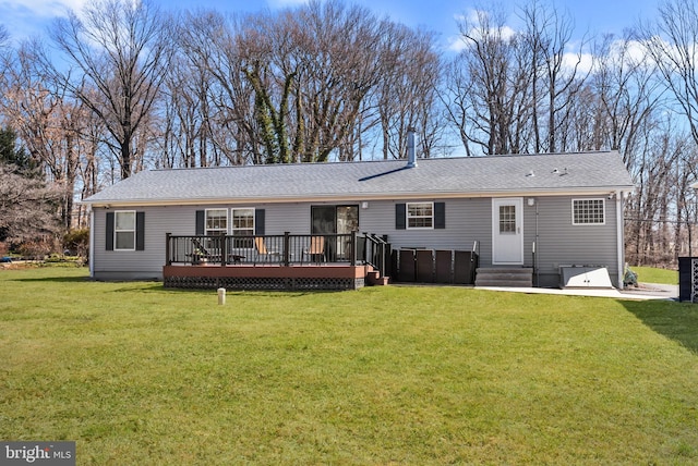 rear view of property featuring a shingled roof, a yard, and a deck