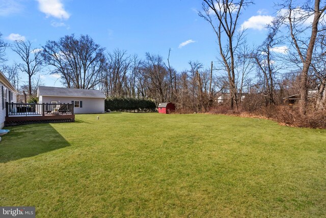 view of yard with an outbuilding, a deck, and a storage shed