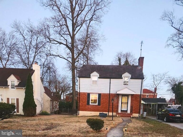 view of front of home featuring a chimney and brick siding