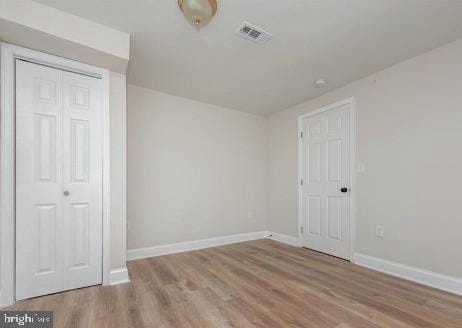 unfurnished room with visible vents, baseboards, and wood finished floors