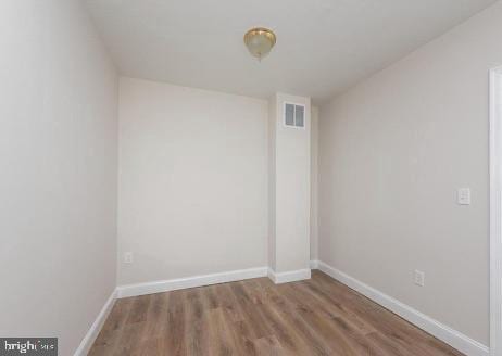 spare room featuring visible vents, baseboards, and wood finished floors