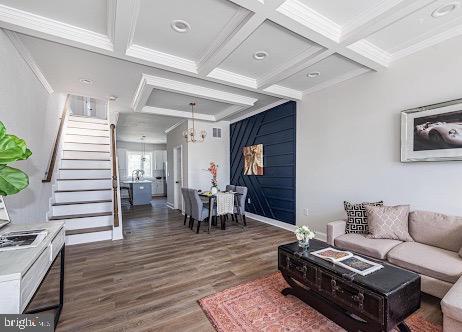 living area with ornamental molding, coffered ceiling, beamed ceiling, and wood finished floors