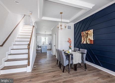 dining space with visible vents, stairway, wood finished floors, and ornamental molding