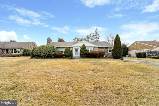 view of front of property with stone siding, a chimney, and a front yard