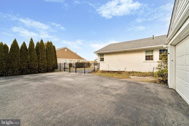 view of side of home featuring a garage, fence, and a gate