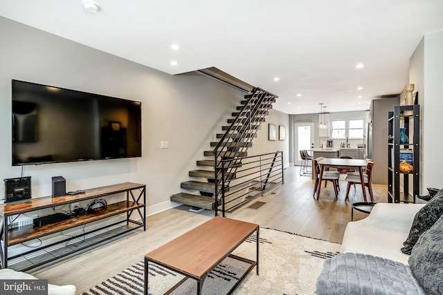 living room featuring stairs, baseboards, light wood-style flooring, and recessed lighting