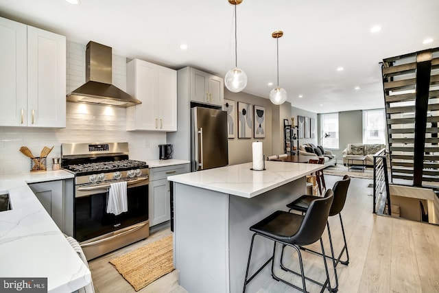 kitchen featuring appliances with stainless steel finishes, tasteful backsplash, wall chimney range hood, and light stone countertops