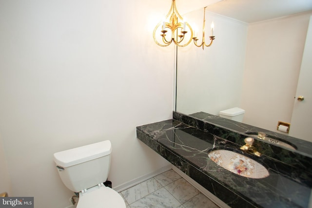 bathroom with toilet, marble finish floor, a chandelier, and a sink