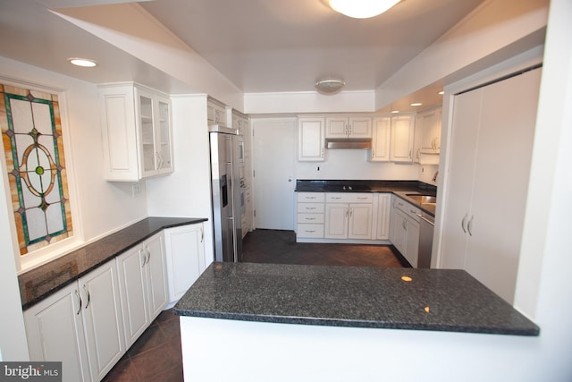 kitchen featuring under cabinet range hood, white cabinetry, stainless steel appliances, a peninsula, and glass insert cabinets