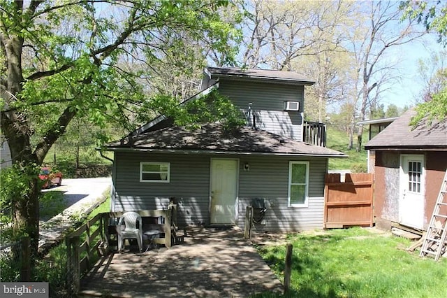 rear view of property featuring a lawn and fence