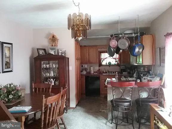 kitchen with an inviting chandelier, black dishwasher, and brown cabinets