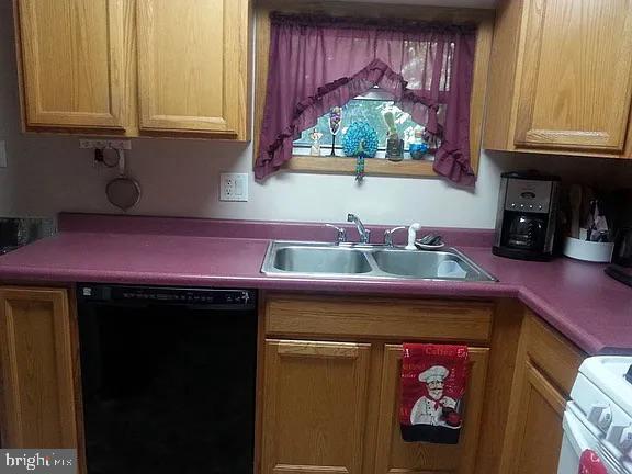 kitchen featuring dishwasher, light countertops, a sink, and range