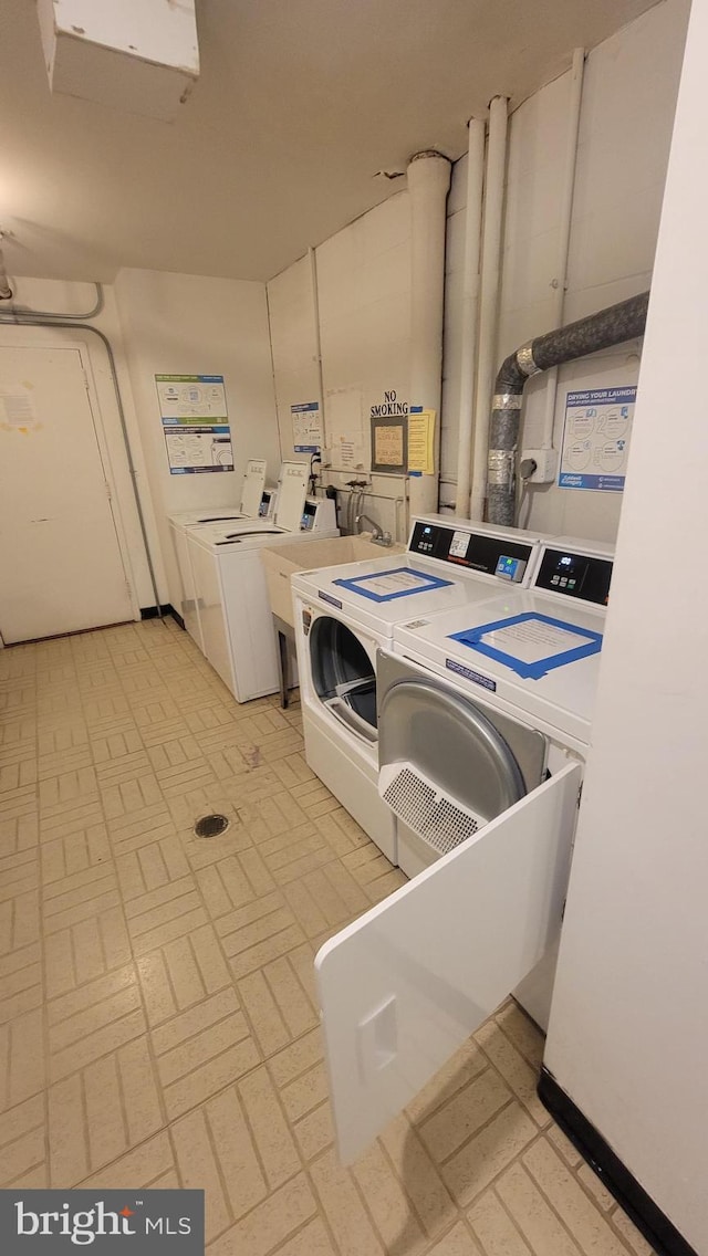 shared laundry area with washer and clothes dryer and brick patterned floor