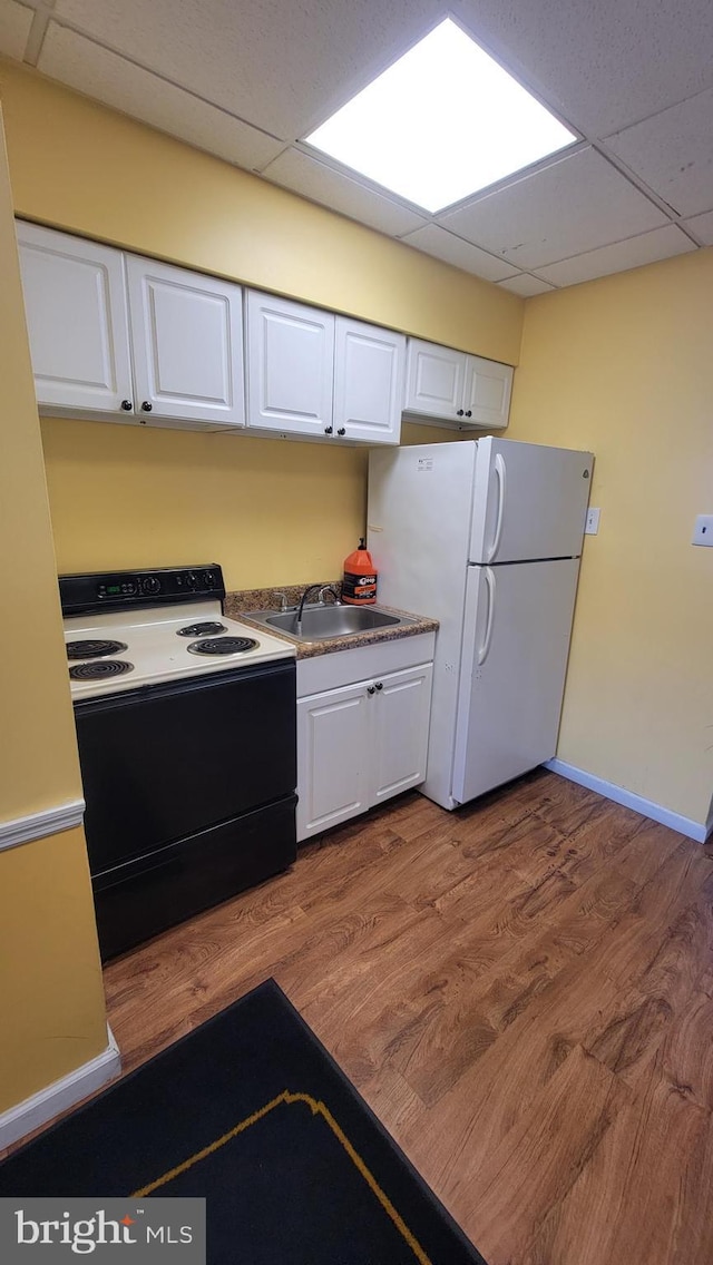 kitchen with range with electric cooktop, white cabinets, freestanding refrigerator, and a sink