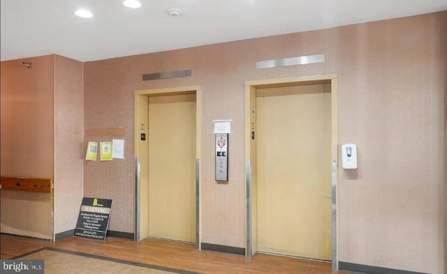 interior space with elevator, recessed lighting, and wood finished floors