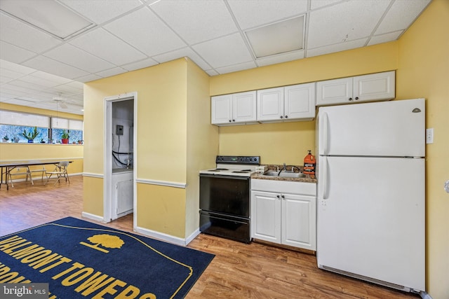 kitchen featuring light wood finished floors, a drop ceiling, electric range oven, freestanding refrigerator, and white cabinetry